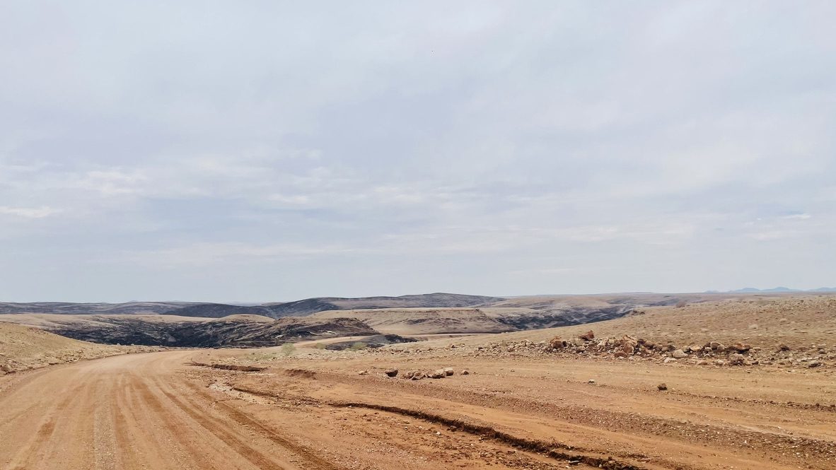 Empty gravel track winding through arid hills